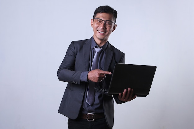 Smiling businessman pointing on a laptop