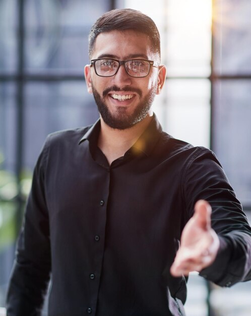 Foto un uomo d'affari sorridente che tende la mano per una stretta di mano.