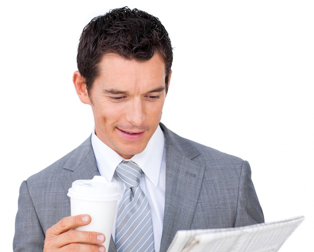 Smiling businessman reading a newspaper while drinking coffee