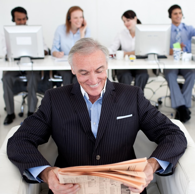 Smiling businessman reading a newspaper 