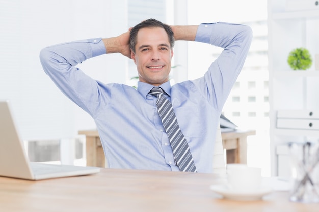 Smiling businessman relaxing on his office 