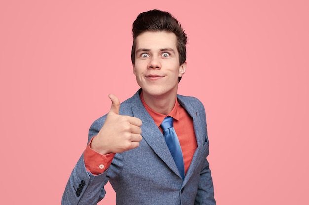 Smiling businessman showing thumb up in studio