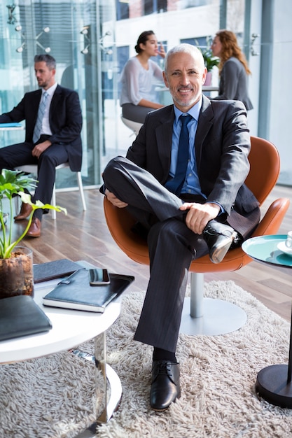 Smiling businessman sitting on chair in office