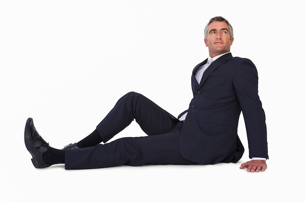 Smiling businessman sitting on the floor on white background