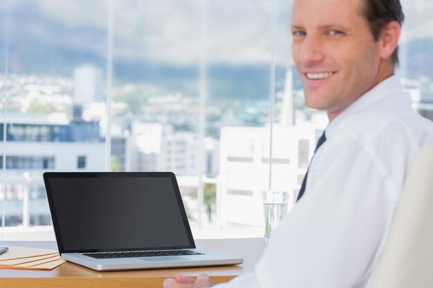 Foto uomo d'affari sorridente che si siede davanti ad un computer portatile