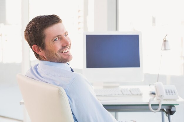 Photo smiling businessman sitting at his desk