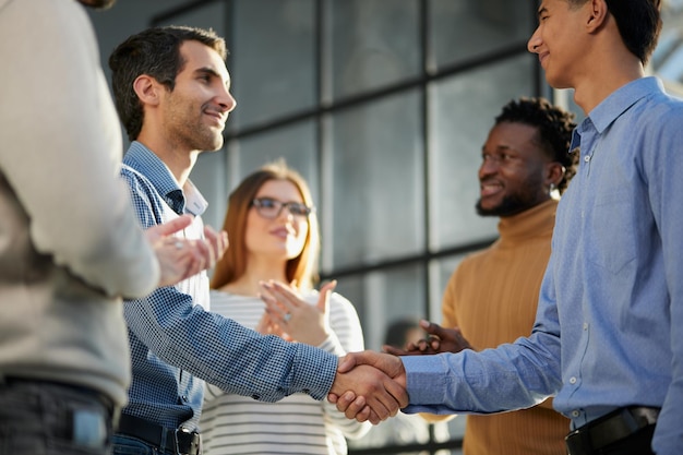 Photo smiling businessman standing greeting partner with handshake