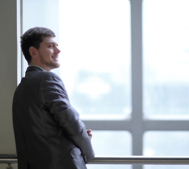 Smiling businessman standing near a large office window