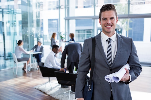 Smiling businessman standing with document at office