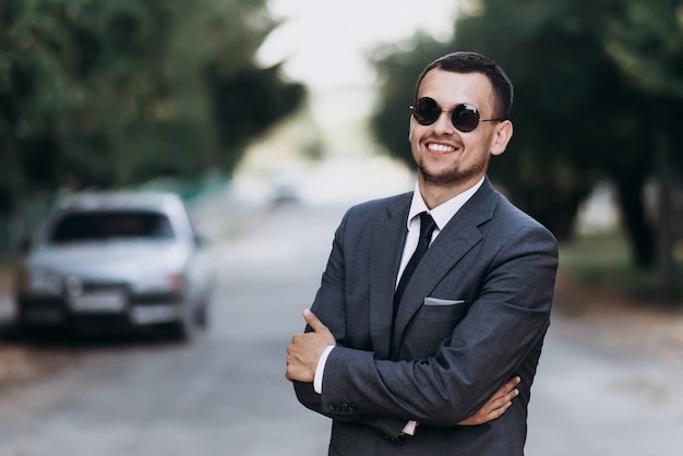 Smiling businessman in suit standing outdoors. Success concept