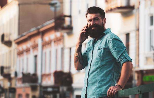 Smiling businessman talking on phone in the city Business man using smartphone on the street Man standing outside a building