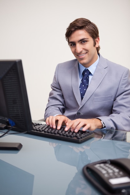 Foto uomo d'affari sorridente che digita sulla sua tastiera