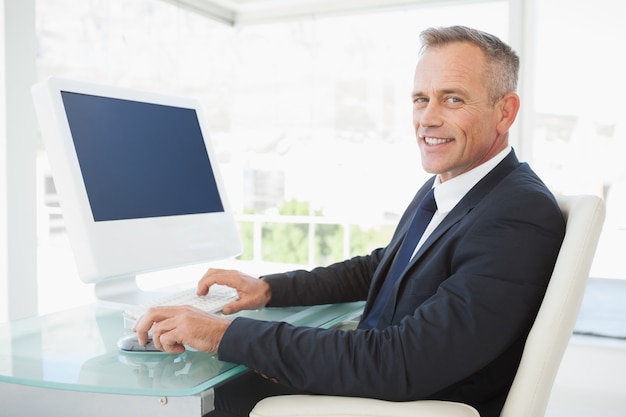 A smiling businessman uses his computer