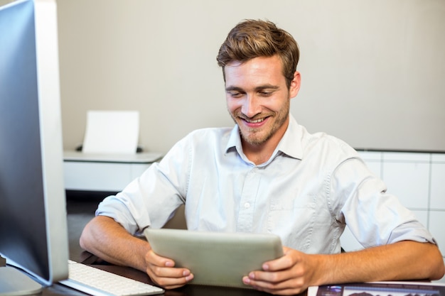 Smiling businessman using digital tablet in office