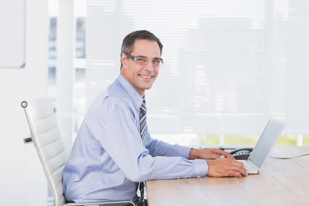 Smiling businessman using his computer 