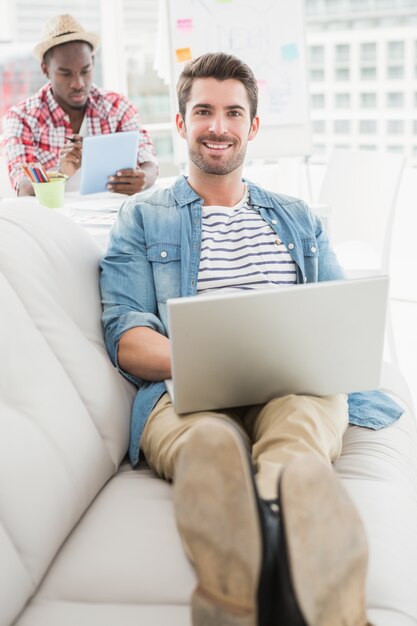 Smiling businessman using laptop on couch