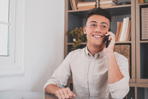 Smiling businessman wearing glasses talking on phone, sitting at desk with laptop, friendly manager consulting customer by phone, happy man chatting with friends distracted from work