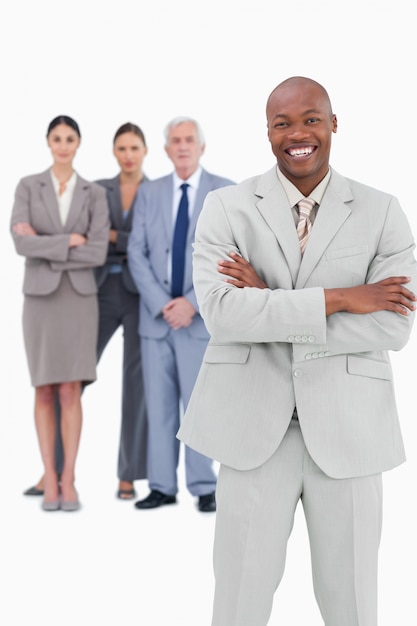 Smiling businessman with arms folded and team behind him