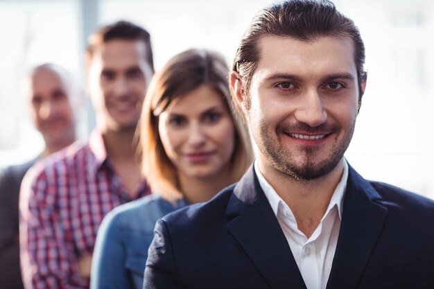 Smiling businessman with coworkers standing in row