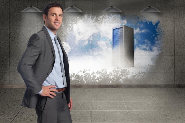 Smiling businessman with hand on hip against splash on wall revealing server tower