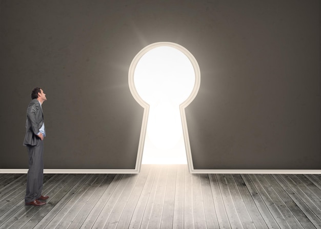 Photo smiling businessman with hands on hips against door revealing bright light