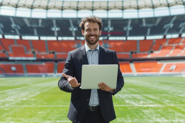 Smiling businessman with laptop giving thumbs up at a soccer stadium