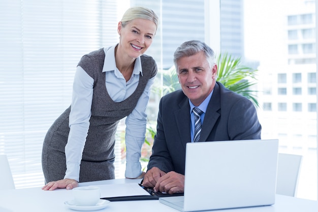 Smiling businessman with secretary checking diary 