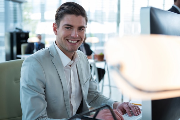 Uomo d'affari sorridente che lavora al computer nell'ufficio