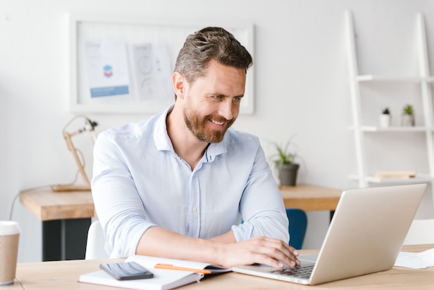 Uomo d'affari sorridente che lavora al computer portatile