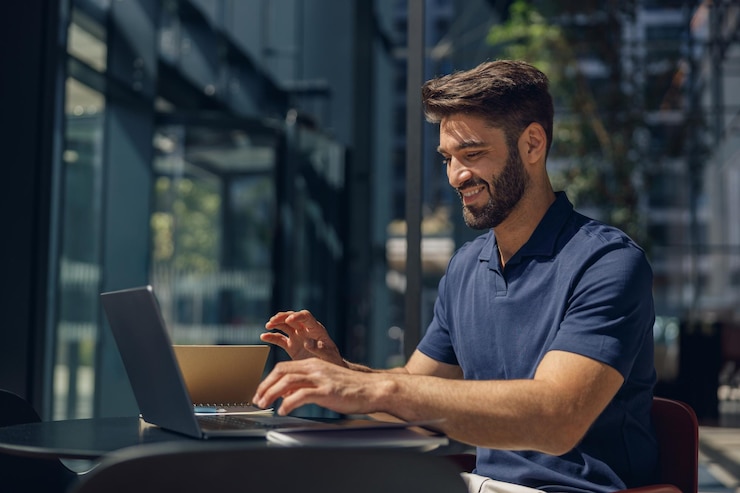 Photo smiling businessman working on laptop sitting on modern office background during working day