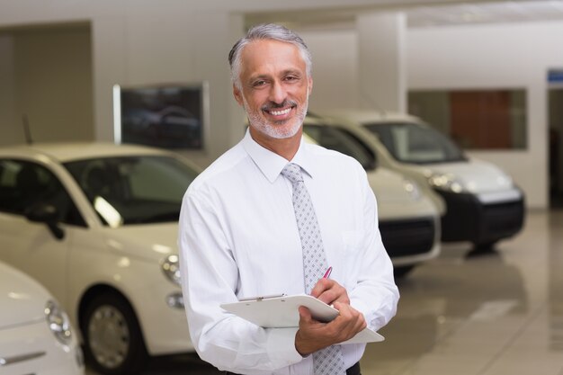 Smiling businessman writing on clipboard