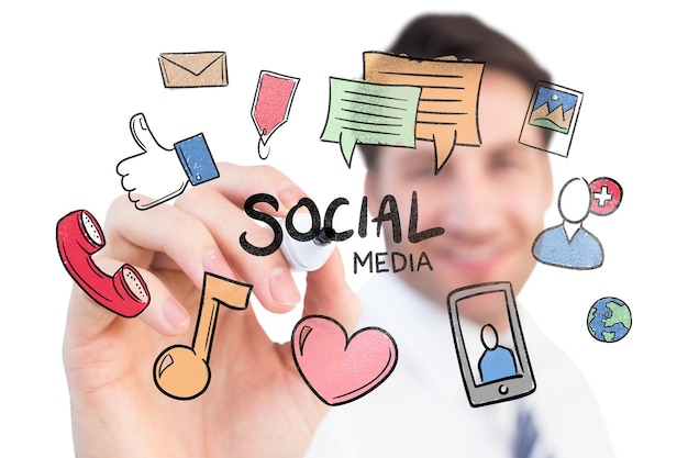smiling businessman writing with black marker against social media doodle