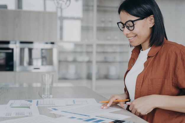 Donna di affari sorridente che analizza le statistiche che lavorano al progetto che prepara la relazione finanziaria alla scrivania