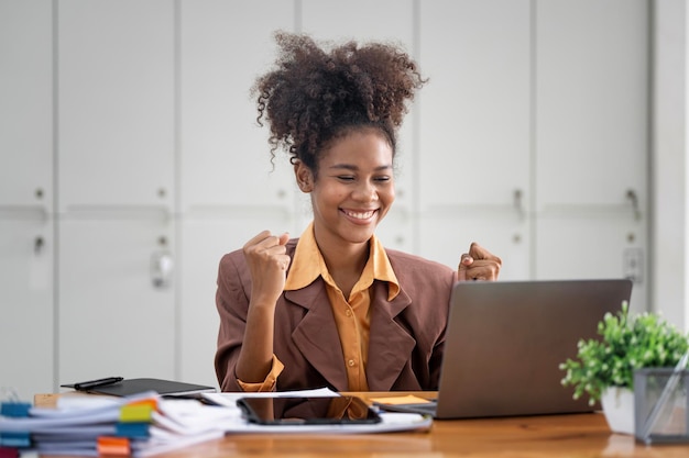 Donna di affari sorridente che celebra il successo in un ufficio