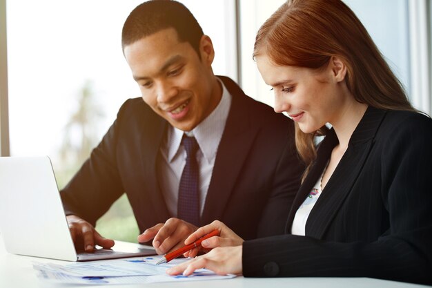 Smiling businesswoman discussing graph with colleague in office