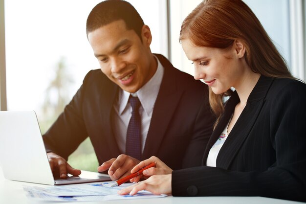 Photo smiling businesswoman discussing graph with colleague in office