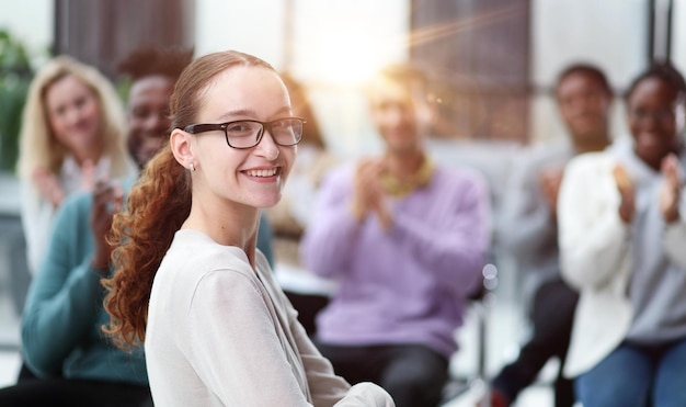 Smiling businesswoman in glasses looking at camera at a seminar