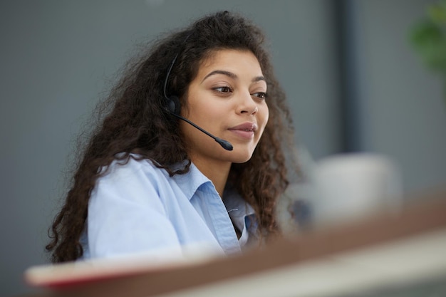 Smiling businesswoman or helpline operator with headset and computer at office