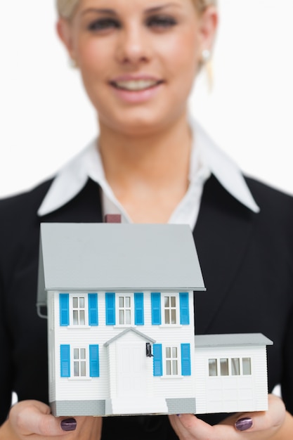 Smiling businesswoman holding a model house