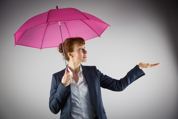 Smiling businesswoman holding pink umbrella