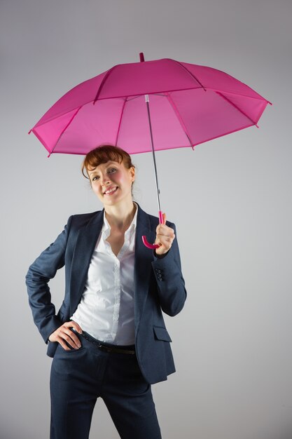 Smiling businesswoman holding pink umbrella