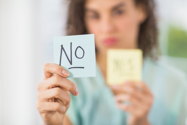 Smiling businesswoman holding yes and no sticks