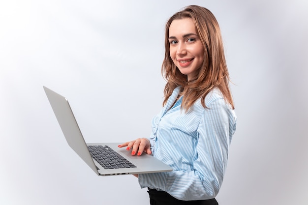 smiling businesswoman holds a laptop isolated on a white wall