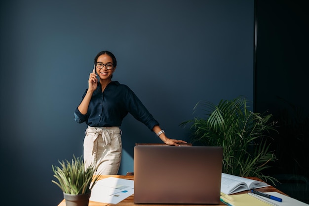 Smiling businesswoman leaning chair talking on smartphone at home