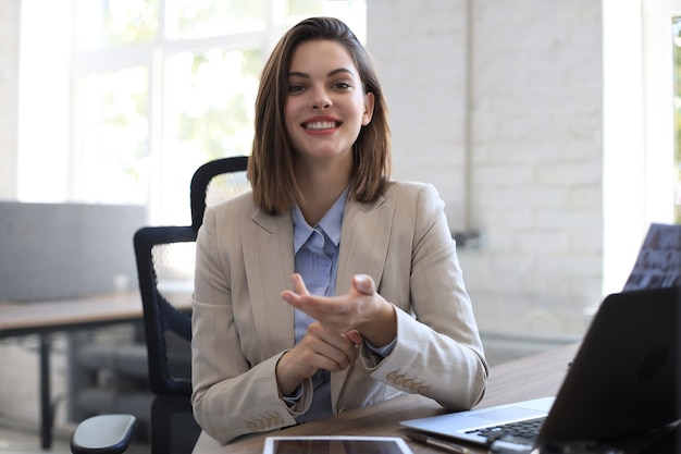 Foto donna d'affari sorridente che guarda la telecamera, fa una conferenza o una chiamata di lavoro, registra un video blog, parla con il cliente.