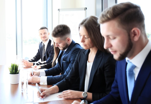 Smiling businesswoman looking at camera at seminar with her colleagues near by