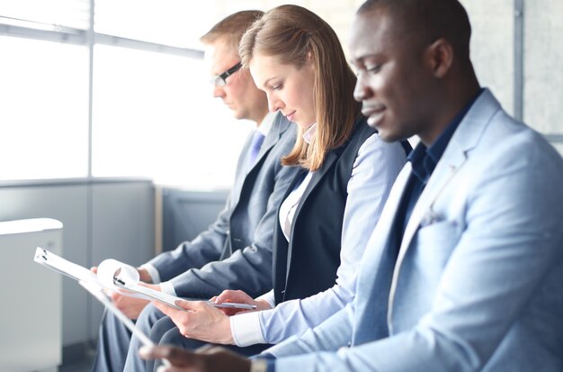 Smiling businesswoman looking at camera at seminar with her colleagues near by