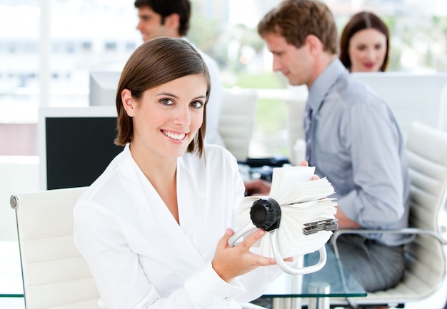 Smiling businesswoman looking for a contact in her white cards 