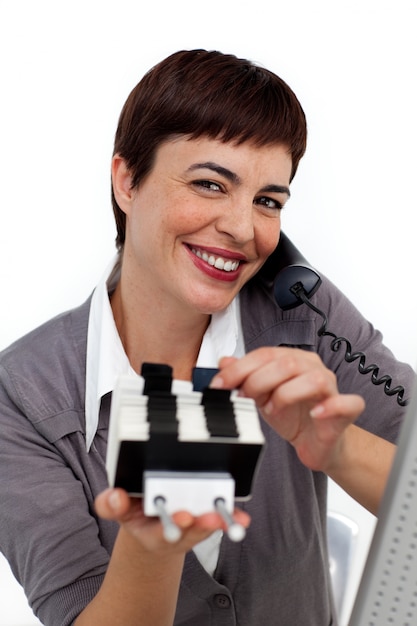 Smiling Businesswoman on phone consulting a business card holder 