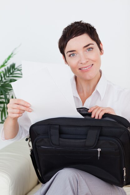 Smiling businesswoman putting some papers in her bag